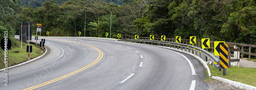 On the way up the mountain, the signaled curve warns drivers with reflective signs and vivid paint. Surrounded by fog and greenery, it demands attention and respect for nature.