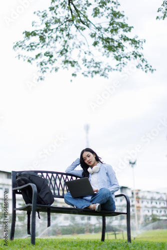 Asian female college student thinking outside with bag and book in a park, Education studying students concept
