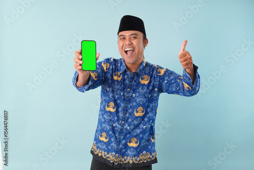 Foto government worker man wearing kopri blue batik uniform He is glasses pointing to copy space on his smartphone