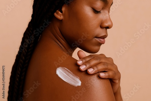 Dark Skinned Woman Applying Hydrating Cream to Her Shoulder in a Moment of Wellness and Self-Care, radiating beauty and confident radiance.