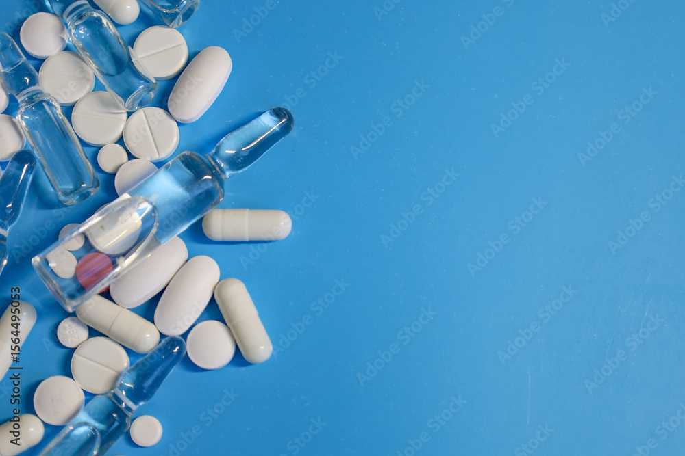 A rich blue background is adorned with a scattering of medical ampoules, white pills, and capsules, arranged in the left part of the frame. The composition symbolizes modern medicine and pharmaceutica A rich blue background is adorned with a scattering of medical ampoules, white pills, and capsules, arranged in the left part of the frame. The composition symbolizes modern medicine and pharmaceutica