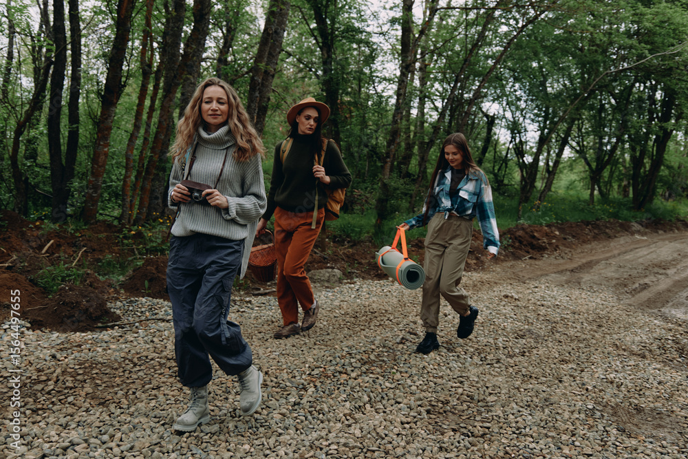 Fototapeta premium Active middle age women walking in forest trail enjoying fitness, health, and wellness together while embracing community and healthy lifestyle outdoors.