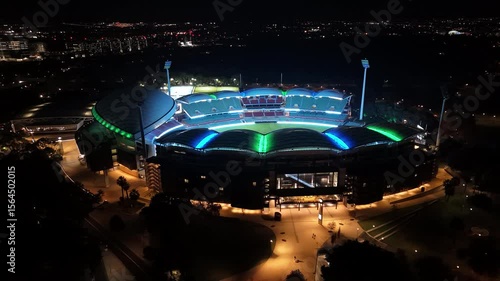 Adelaide Oval, South Australia, 2 Jul 2025: 4K Nighttime Aerial Drone Footage of the Famous Sports Stadium Illuminated in Colourful Lights, Capturing Roof Design, Seating Tiers, and Surrounding City