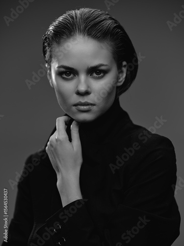 фотографія black and white portrait of a serious woman with intense gaze wearing dark cloth