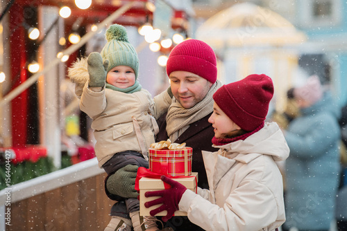 father and two children stroll through a city Christmas market