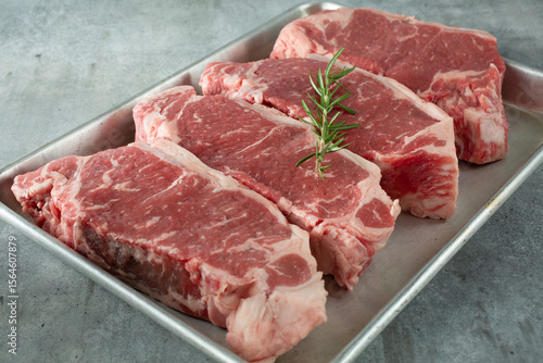 A view of a four choice New York steaks, on a baking sheet.