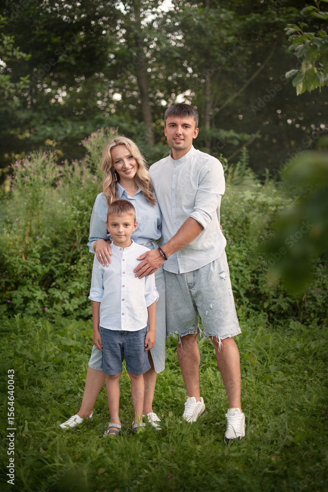 Fototapeta premium A beautiful family, mom, dad, and son in nature. looking at the camera