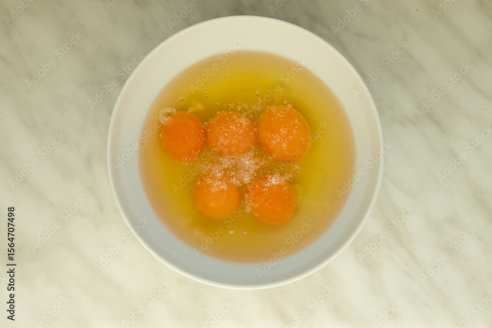 five cracked and salted eggs in white bowl on marble surface five cracked and salted eggs in white bowl on marble surface