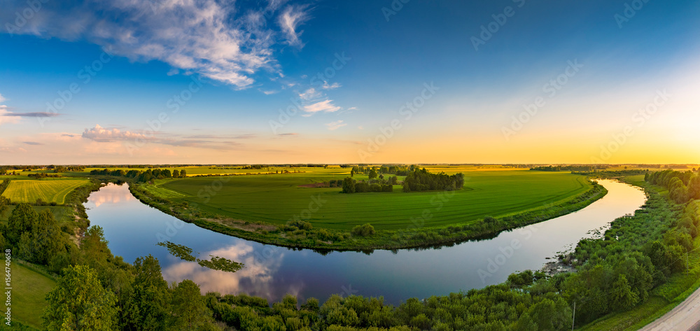 Obraz premium Aerial view of beautiful sunset in countryside with river and grain fields