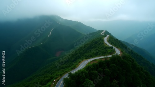 A high-resolution aerial view of a winding mountain road cutting through lush green hills covered with dense vegetation.