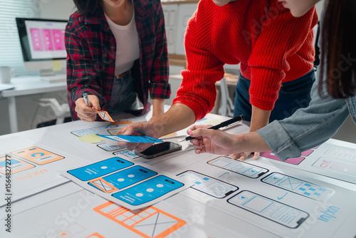 Photos Three Asian ux designers are discussing and improving the design of a mobile app