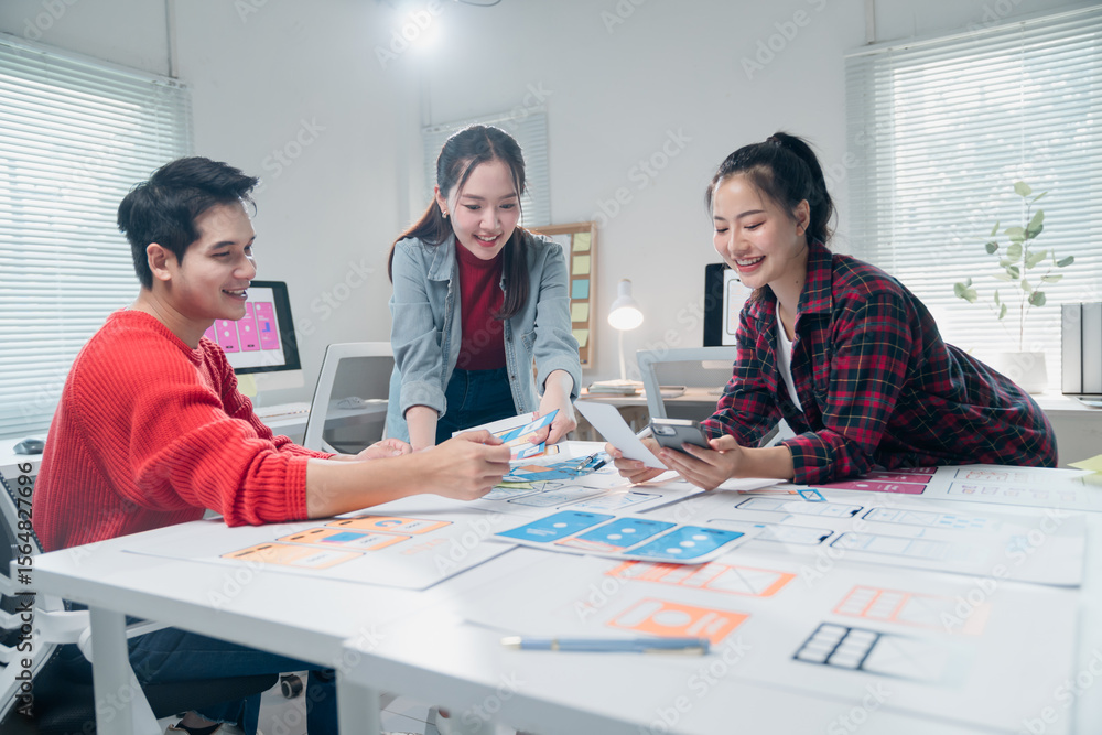 Fototapeta premium Diverse group of young professionals engaging in a collaborative design session. They are reviewing digital project layouts and brainstorming ideas in a modern office setting