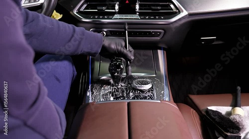 Men's manual cleaning of the interior and upholstery of the car with a brush for parts. The concept of detailing the car. Car wash background.