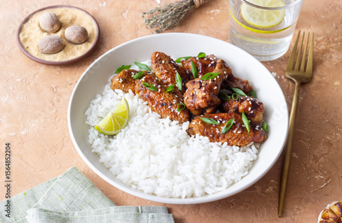 Chicken wings in teriyaki sauce with rice, sesame and onion. Asian food.