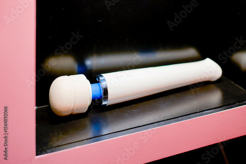 White and blue modern massage wand on a black and pink shelf.