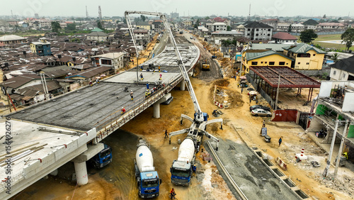 Aerial view of a modern flyover under construction with heavy machinery contrasting against the residential buildings, Port Harcourt, Rivers, Nigeria.