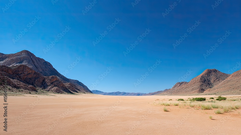 Naklejka premium Vast Desert Landscape with Mountains under Clear Blue Sky