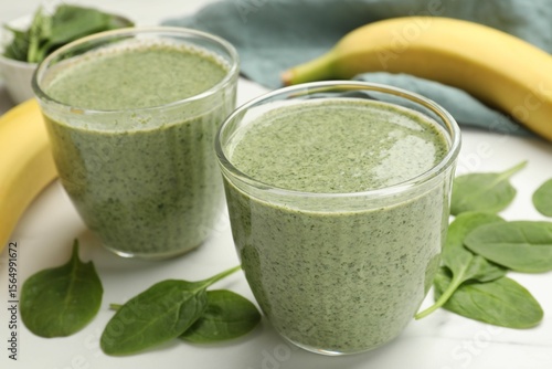 Photos Tasty spinach smoothie and ingredients on white table, closeup