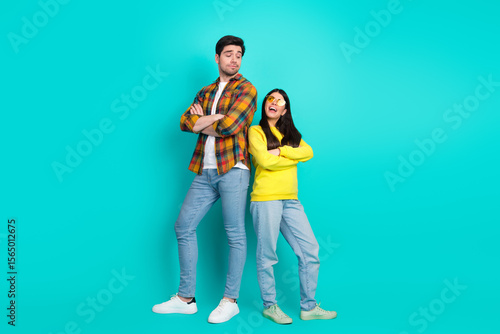Happy couple standing confidently against turquoise background showcasing casual style and playful expressions