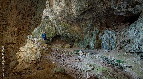 Foto A hiker rests in the spacious interior of Három-kúti Cave, a prehistoric archaeological site in the Bükk Mountains with a wide, natural entrance