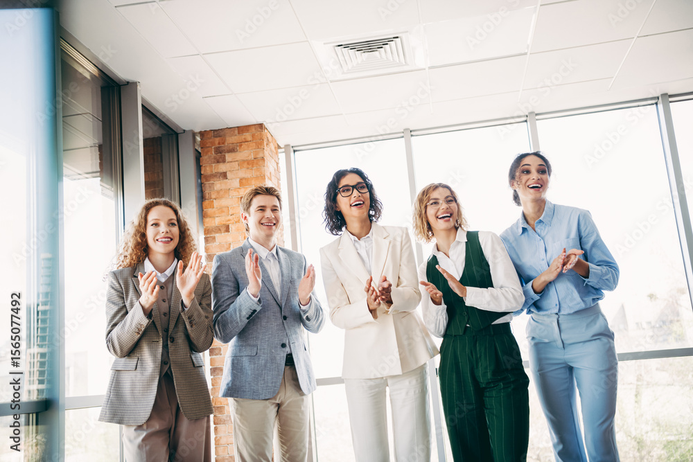 Obraz premium Group of professional coworkers applauding during a team meeting in a modern office space, celebrating success