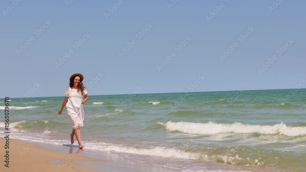 A young woman in a white dress and straw hat walks along the sandy beach, enjoying the refreshing waves of the ocean under a clear sky. A young woman in a white dress and straw hat walks along the sandy beach, enjoying the refreshing waves of the ocean under a clear sky.