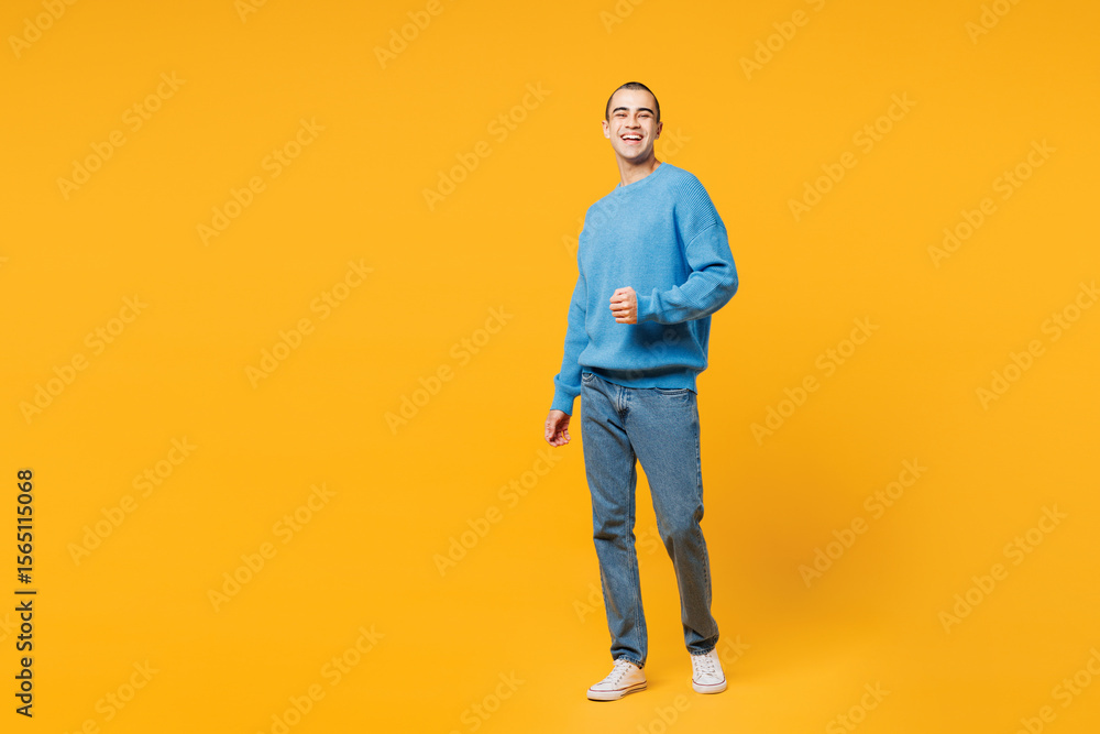 Fototapeta premium Full body young smiling happy middle eastern man he wearing blue sweatshirt casual clothes walking going looking camera isolated on plain yellow orange background studio portrait. Lifestyle concept.
