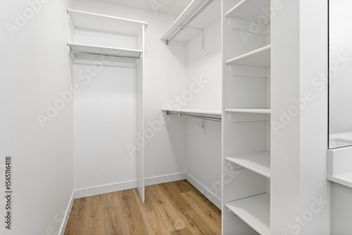 Small white closet with a wooden floor and white shelves