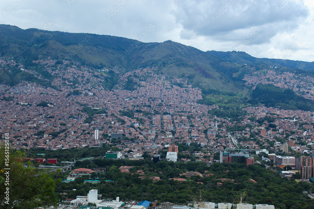 Naklejka premium photograph taken of the city of Medellin from one of its hills with a view towards its high and low-income neighborhoods. city in the middle of a valley and surrounded by mountains, and in the backgro