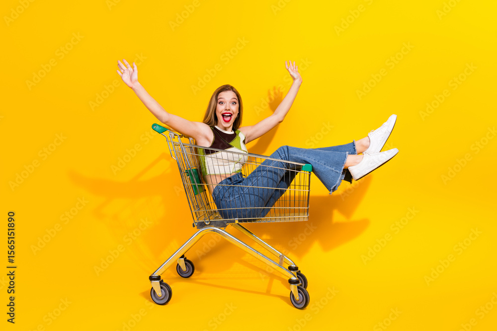 Φωτογραφία Excited young woman in casual outfit sitting playfully in a shopping cart with h