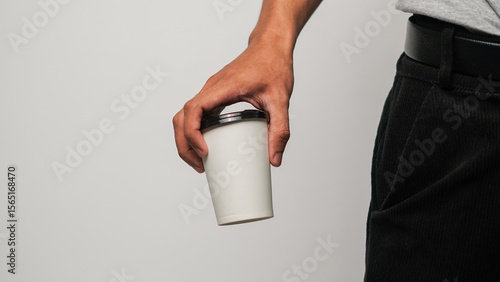 Person's hand holding a minimalist white reusable coffee cup, studio shot on clean background, eco-friendly drinkware