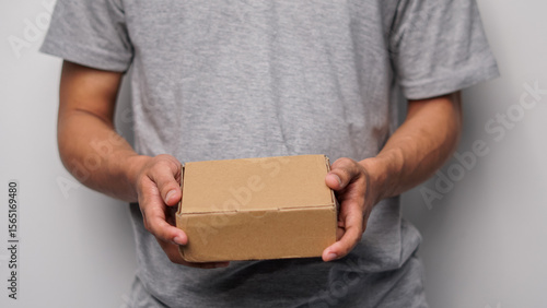 Person's hands holding a small blank brown cardboard box, ideal for delivery or packaging concepts