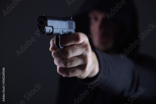 Masked Man Pointing Gun in Threatening Gesture on Dark Background Security and Crime Concept