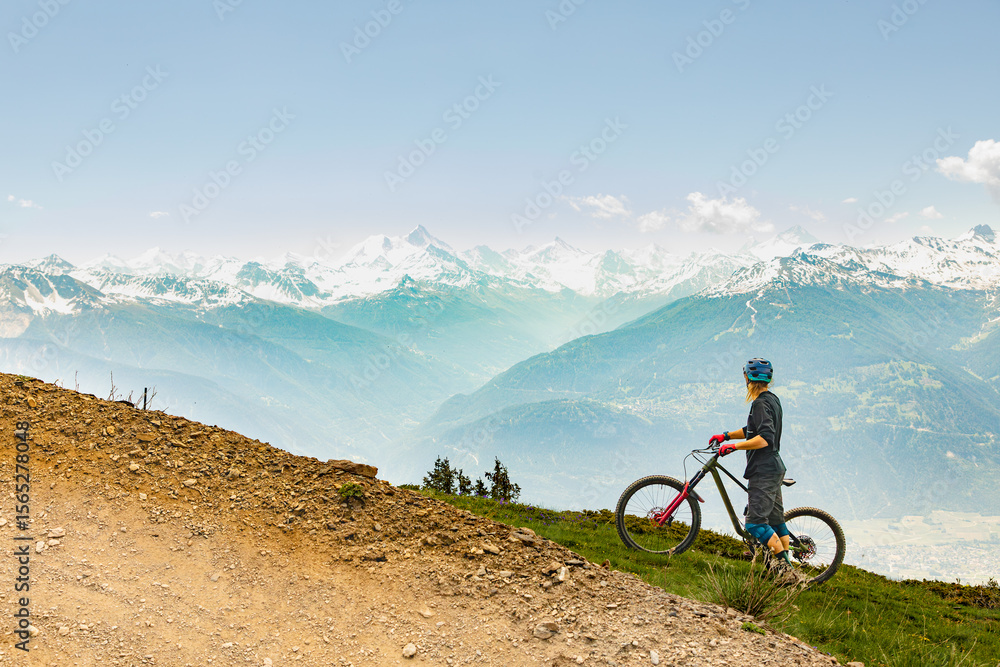 Biker enjoys breathtaking alpine view while paused Biker enjoys breathtaking alpine view while paused