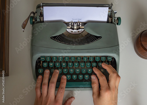 Author is typing on a vintage turquoise typewriter, crafting a new story on a clean white desk, with the paper displaying the intriguing start of their work the thie