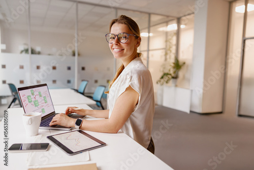 A young woman focuses on her laptop in a bright, modern office that inspires her creativity and productivity