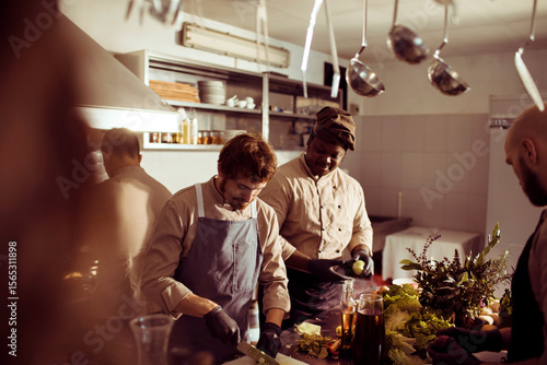 Professional chefs preparing food together in a busy restaurant kitchen