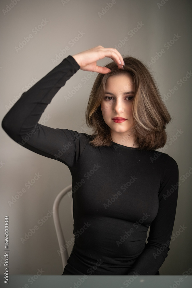 Portrait of a young beautiful long-haired girl in dark clothes in an interior studio. Portrait of a young beautiful long-haired girl in dark clothes in an interior studio.