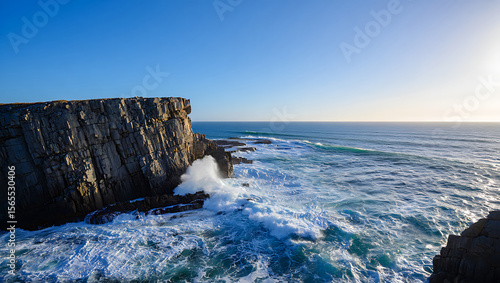 Rugged coastal cliffs meet crashing ocean waves under a clear blue sky rock water