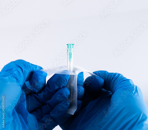 Foto Gloved hands opening a sterile needle from its blister packaging