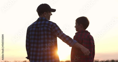father and son silhouette at sunset shows father s loving embrace and strong bond outdoors. father shares warmth and care with son, capturing emotional connection during peaceful family moment.