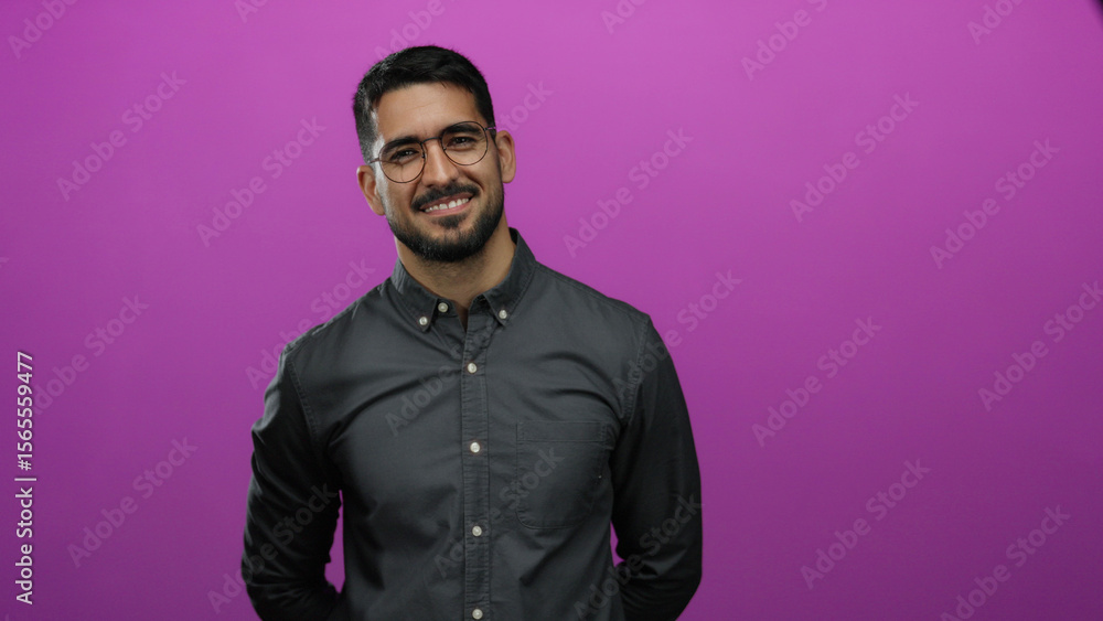 Obraz premium Man smiling confidently against a vibrant pink background in a portrait with glasses and dark hair wearing a casual shirt creating a stylish and modern composition