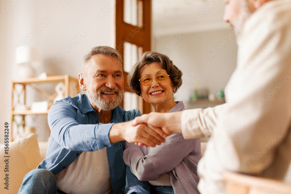 Fototapeta premium Satisfied senior spouses making sale purchase deal, handshaking with real estate agent agreeing to buy new house at meeting