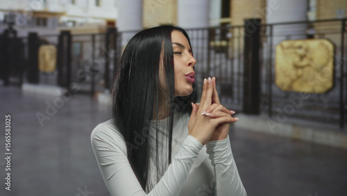 Wallpaper Mural Hispanic woman outdoors playfully making pretend shooting gestures with hands in a white shirt against an urban backdrop, expressing a fun and confident demeanor. Torontodigital.ca