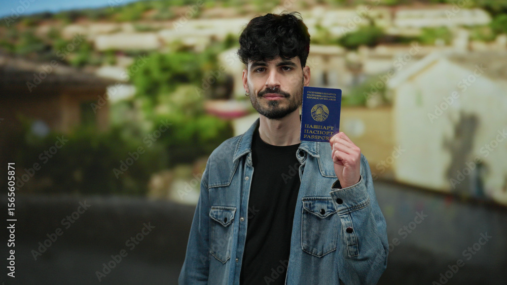 Man holding belarus passport standing on urban street in casual denim, showcasing identity and travel readiness against blurred cityscape background. Man holding belarus passport standing on urban street in casual denim, showcasing identity and travel readiness against blurred cityscape background.