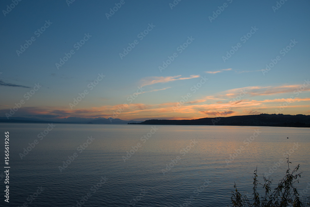 Fototapeta premium Serene Lake Taupo at dusk, with soft pastel hues reflecting on the calm water, capturing a peaceful and expansive natural beauty.