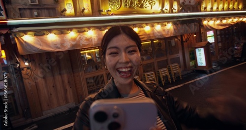 Photography A young woman smiles and waves while talking on a video chat on her mobile phone