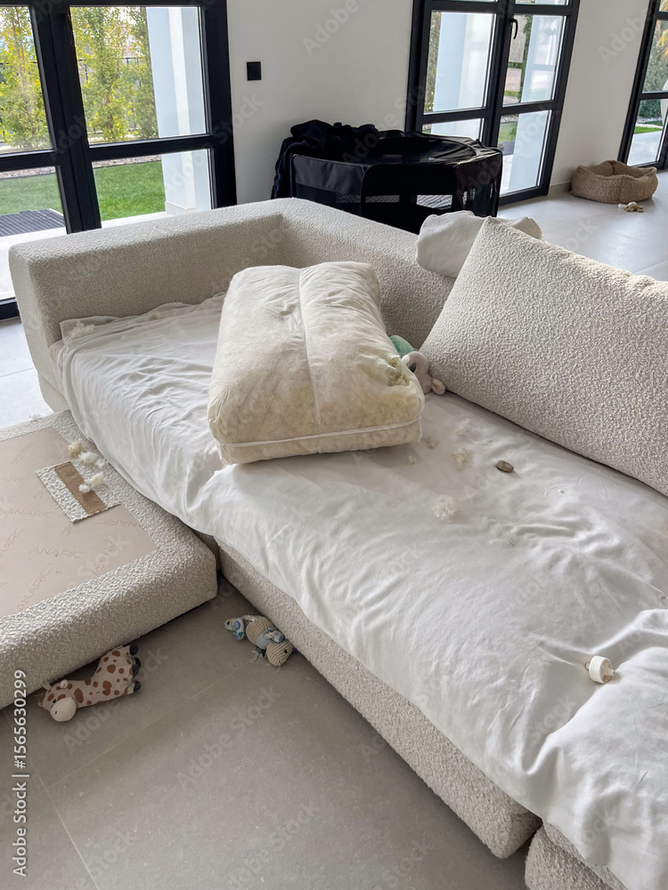 Obraz premium Mischievous puppies create chaos on a couch, leaving behind a fluffy aftermath of destruction and mystery in a cozy home environment filled with soft textures and scattered toys