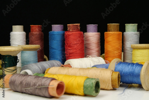 Spools with multi-colored threads on black background, close-up shot