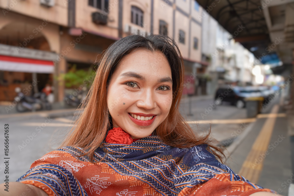 Fototapeta premium Beautiful Asian woman smiling sweetly taking a selfie using the camera. Happy woman in the city.